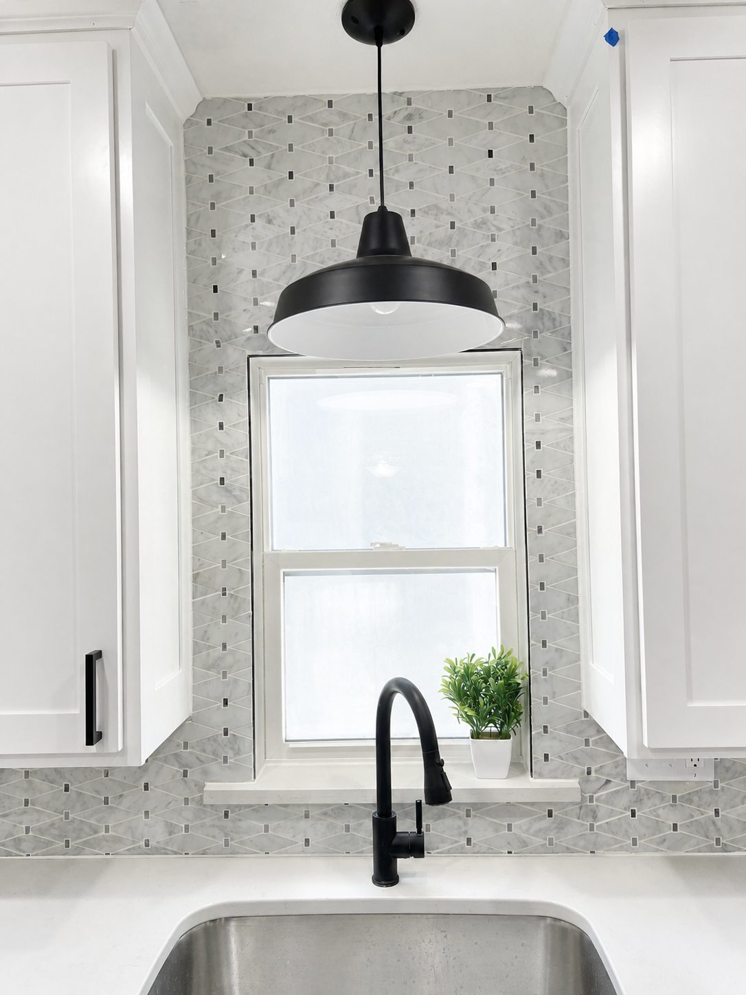 Kitchen sink, tile backsplash, and window in the lower home